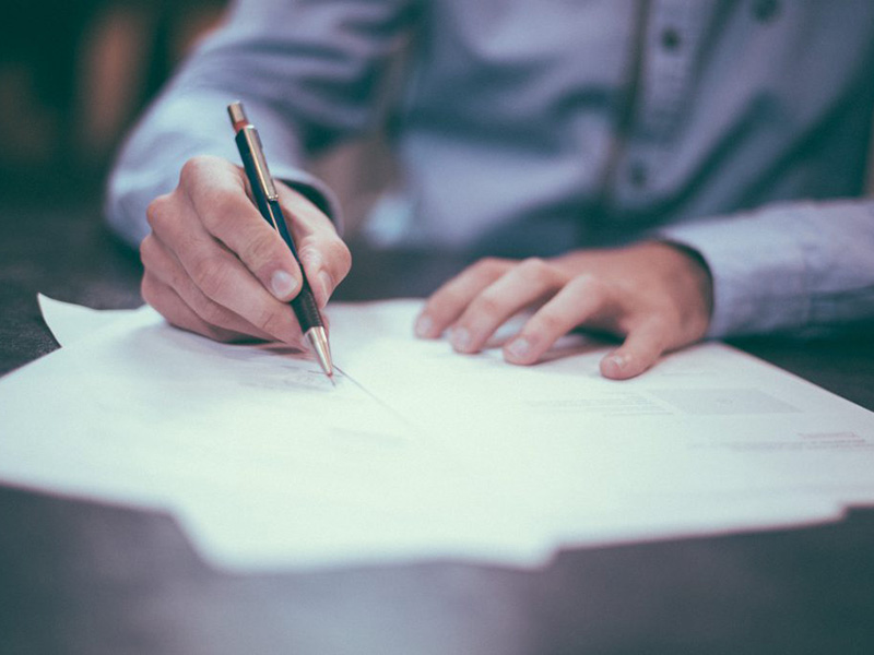 Close-up of hands signing a Legal document - Richards & Richards Law Firm