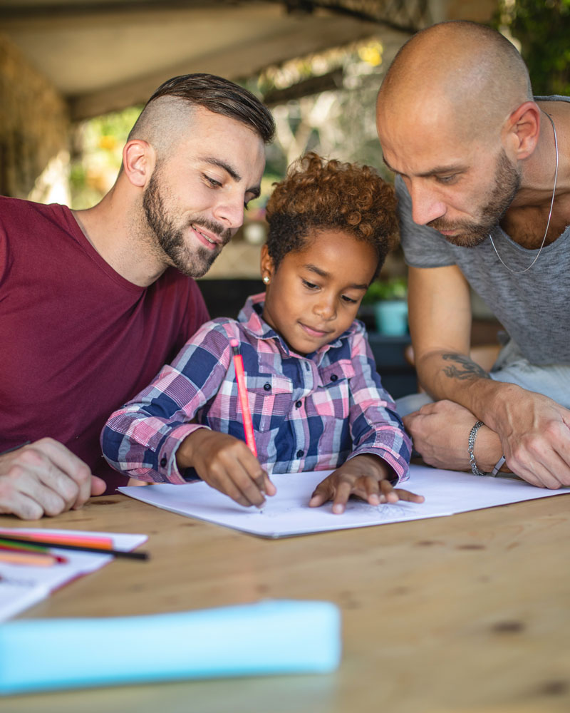 Two dads bonding with their adopted child by coloring a book in Ogden, UT
