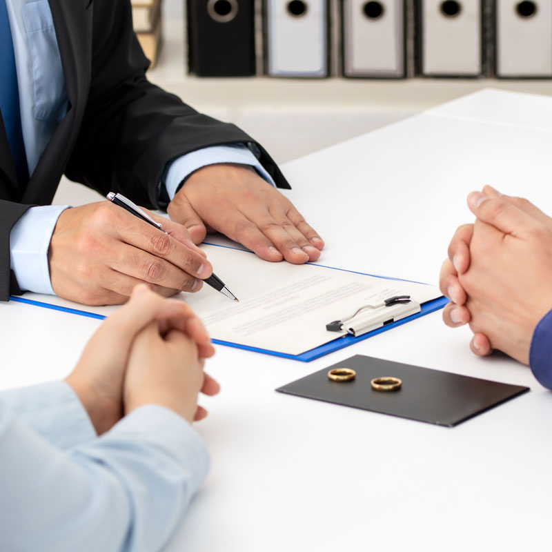 Experienced Annulment Lawyer discussing with a couple, with two wedding rings on the desk in Ogden, UT.
