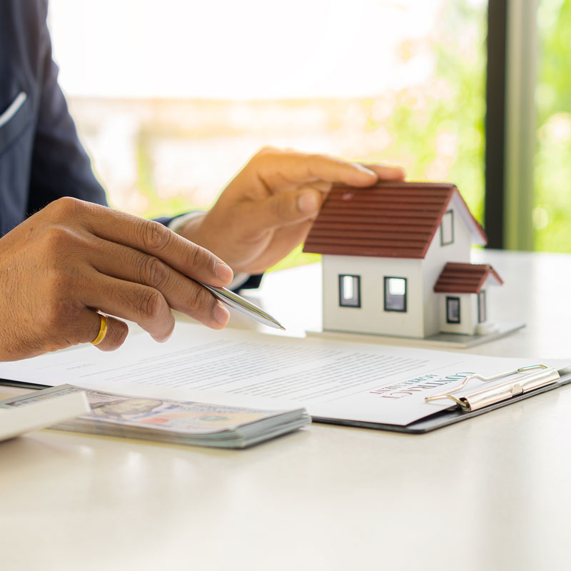 Lawyer in Los Angeles, CA explaining estate planning to the client with documents and small house model