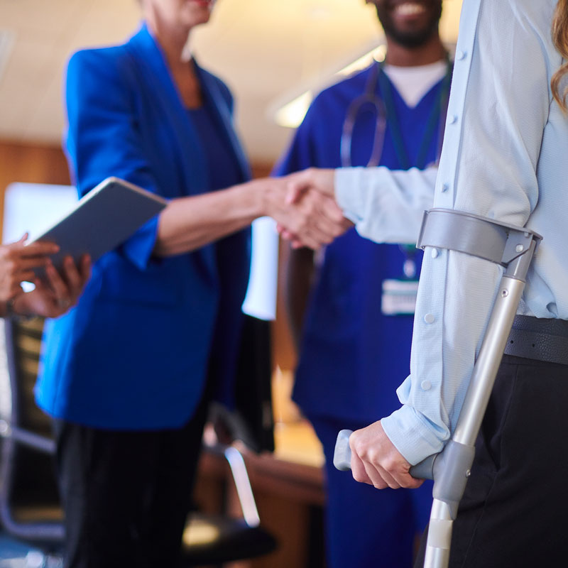 An injured person with a crutch shaking hands with a lawyer in Los Angeles, CA