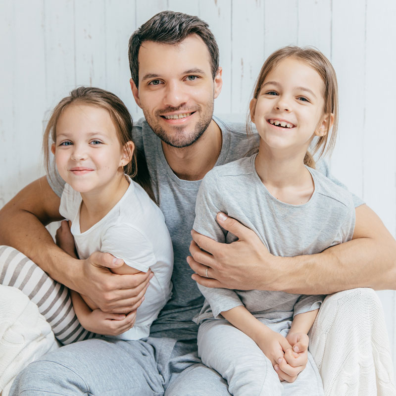 Dad in Ogden, UT hugging his two daughters, symbolizing fathers' rights in paternity disputes