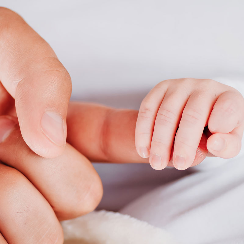 Baby tightly gripping father's finger showing bond for a paternity law in Ogden, UT